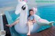 A woman sitting on an inflatable unicorn floating in a pool.