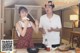 A man and a woman standing in front of a table with food.