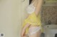 A woman in a yellow and white lingerie standing in a bathroom.