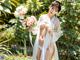 A woman in a white kimono holding a bunch of flowers.