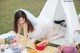 A woman in a white dress sitting on a picnic blanket.