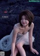 A woman in a white dress sitting on a rock.
