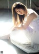 A woman in a white dress sitting on the floor.