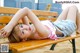 A woman laying on a wooden bench on the beach.