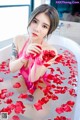 A woman in a bathtub filled with rose petals.