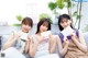 Three young women sitting on a couch holding up cards.