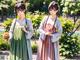 A couple of women standing next to each other in a park.